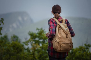 Günbatımı sisli dağ tepe üzerinde zevk sırt çantası ile yenilikçi genç kız.