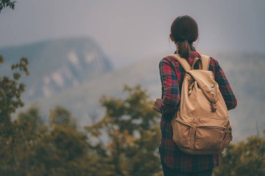 Günbatımı sisli dağ tepe üzerinde zevk sırt çantası ile yenilikçi genç kız.