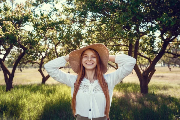 Menina em um chapéu de palha viaja prados verdes — Fotografia de Stock