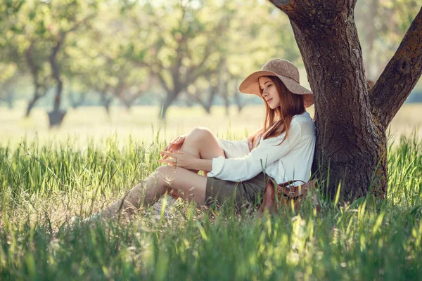 Menina em um chapéu de palha viaja prados verdes — Fotografia de Stock