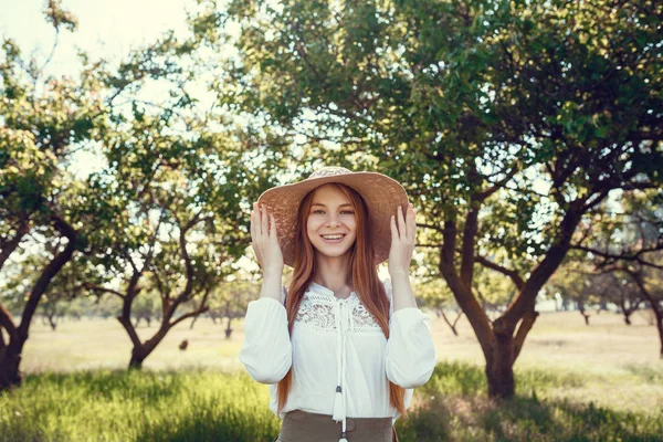 Muchacha joven en un sombrero de paja viaja prados verdes —  Fotos de Stock