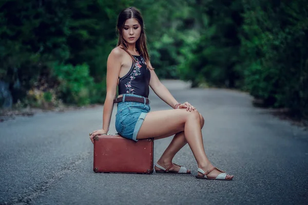 Mujer bastante joven haciendo autostop a lo largo de un camino. — Foto de Stock