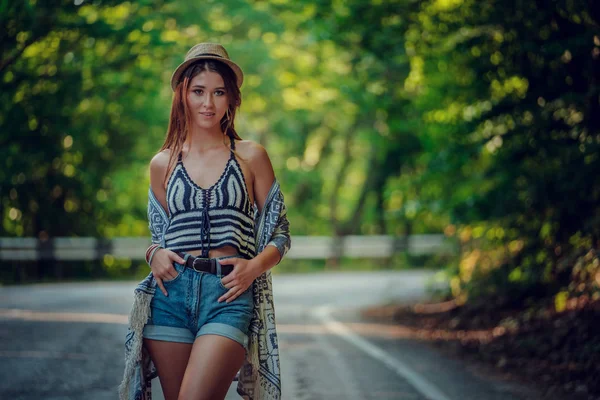 Pretty young woman hitchhiking along a road.