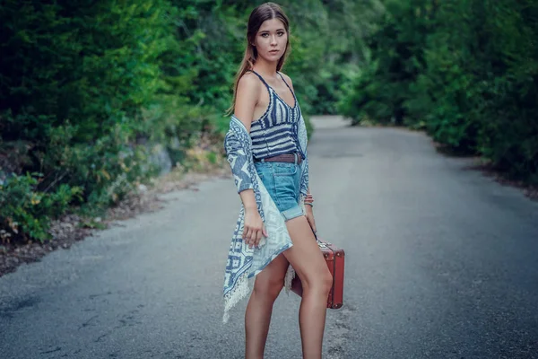 Mujer bastante joven haciendo autostop a lo largo de un camino. — Foto de Stock