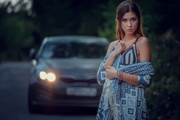 Pretty young woman hitchhiking along a road.