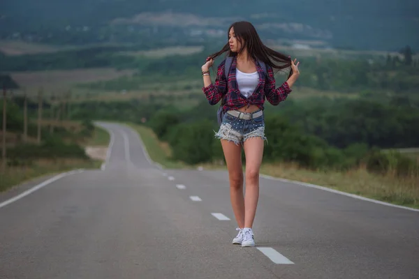 Women is hailing a car on a road. Thumbing a ride. Outdoors vaca — Stock Photo, Image