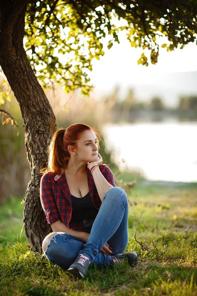 迷人的年轻女子在公园外享受她的时光，背景是日落. — 图库照片