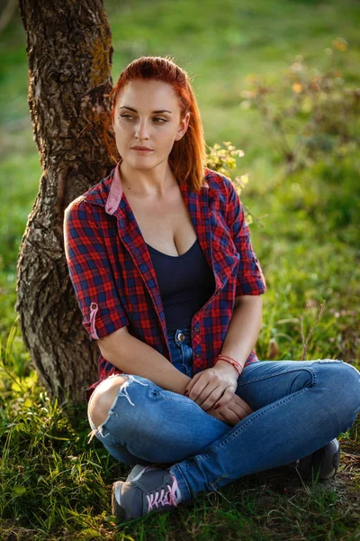 Atractiva joven disfrutando de su tiempo al aire libre en el parque con puesta de sol en el fondo. —  Fotos de Stock