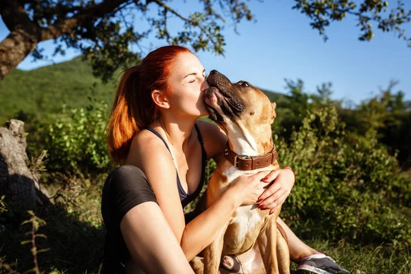 Rothaarige fröhliche junge Mädchen streichelt ihren Hund im Park — Stockfoto