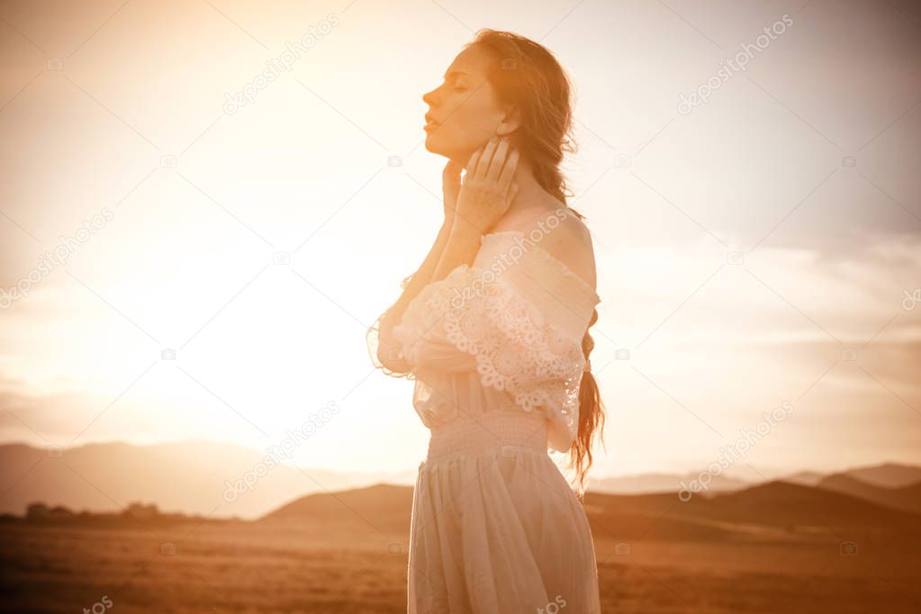 red-haired girl in a field of wheat in a white dress smiles a lo