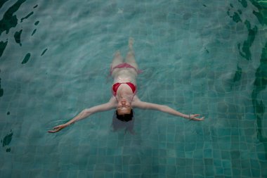 Güzel kız güneşli bir günde yüzme havuzunda dinleniyor.