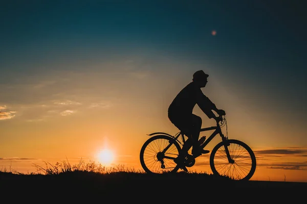 Silhouet van een mannelijke mountainbiker bij zonsondergang in de bergen — Stockfoto
