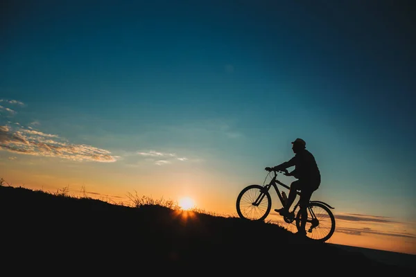 Silhouette of a male mountainbiker at sunset in the mountains — Stock Photo, Image