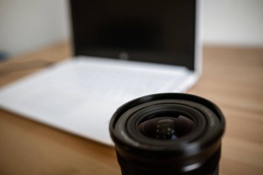 Bir fotoğraf makinesi ile birlikte ahşap bir masa üzerinde bir DSLR lens, bilgisayar.
