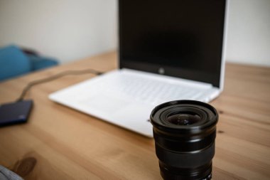 Bir fotoğraf makinesi ile birlikte ahşap bir masa üzerinde bir DSLR lens, bilgisayar.