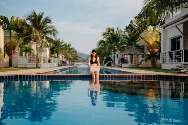 Güneşli bir günde havuz kenarında onu laptop kullanan kadın