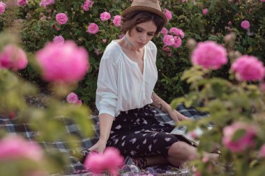 güzel kız kitabı ile şapka giymiş çim üzerinde oturan gül gaden