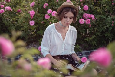 güzel kız kitabı ile şapka giymiş çim üzerinde oturan gül gaden