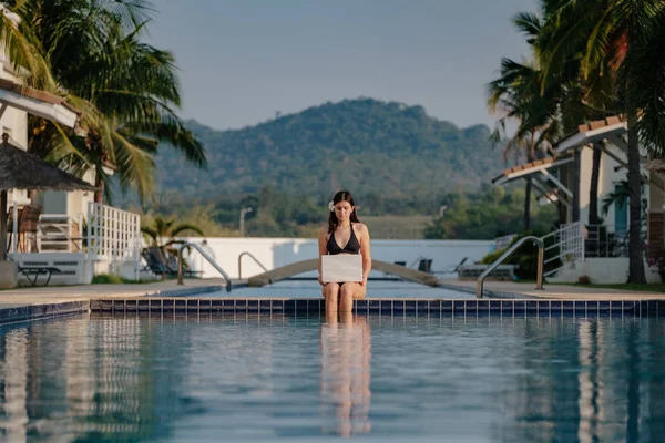 Güneşli bir günde havuz kenarında onu laptop kullanan kadın