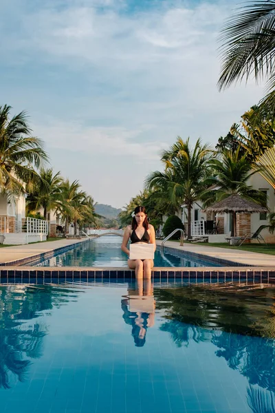 Güneşli bir günde havuz kenarında onu laptop kullanan kadın