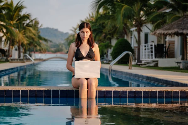 Güneşli bir günde havuz kenarında onu laptop kullanan kadın