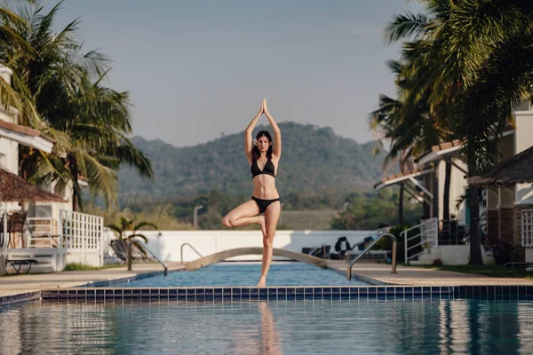 Genç kadın uygulama yüzme havuzunda Yoga poz