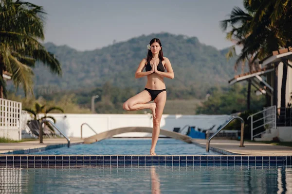 Genç kadın uygulama yüzme havuzunda Yoga poz