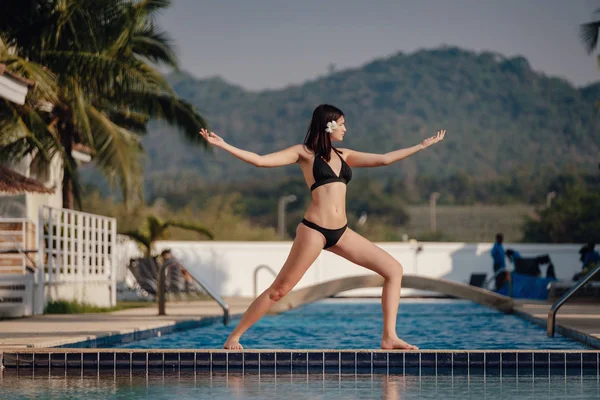 在游泳池练习姿势瑜伽的年轻女子 — 图库照片