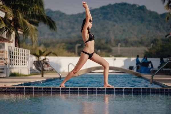 Genç kadın uygulama yüzme havuzunda Yoga poz