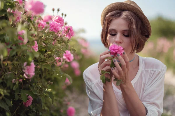 Mooi meisje draagt hoed met boek zittend op gras in Rose gaden — Stockfoto