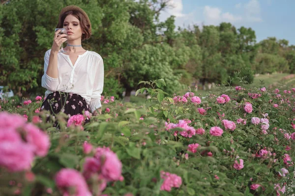 Güllerin yanında poz veren kıvırcık saçlı güzel bir kadın.