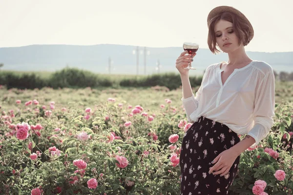 Güllerin yanında poz veren kıvırcık saçlı güzel bir kadın.