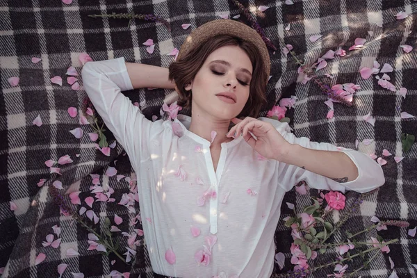 Güllerin yanında poz veren kıvırcık saçlı güzel bir kadın.