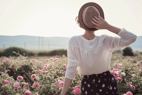 Güllerin yanında poz veren kıvırcık saçlı güzel bir kadın.