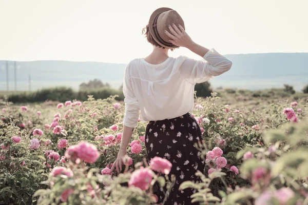 Güllerin yanında poz veren kıvırcık saçlı güzel bir kadın.