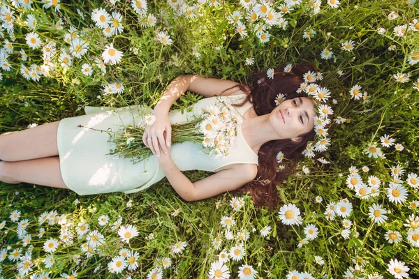 Die schöne Frau liegt im Feld der Kamillen — Stockfoto