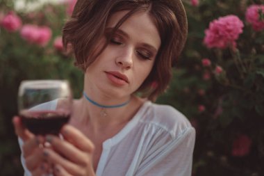 Güllerin yanında poz veren kıvırcık saçlı güzel bir kadın.