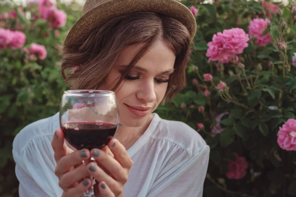 Schöne junge Frau mit lockigem Haar posiert in der Nähe von Rosen — Stockfoto