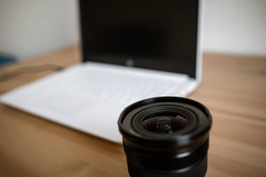 Bir fotoğraf makinesi ile birlikte ahşap bir masa üzerinde bir DSLR lens, bilgisayar.
