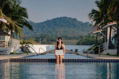 Güneşli bir günde havuz kenarında onu laptop kullanan kadın