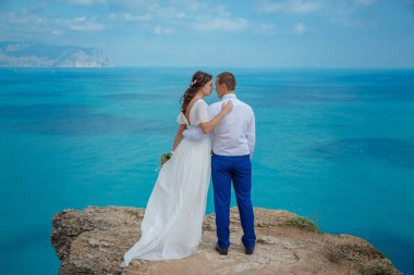 Gelinlik içinde deniz kayalar üzerinde güzel bir çift. Sadece arkadan evli görünümü.
