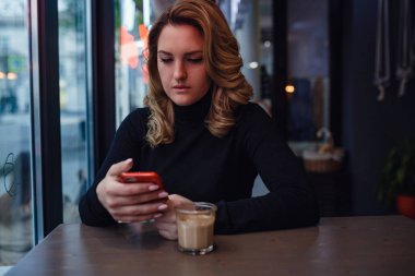 Kahvesinde bir fincan kahveyle gülümseyen kadın..