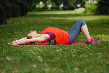 Genç bir kadın parkta özel bir silindir ile uzanan yok.