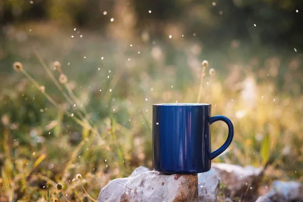 Blue mug of hot tea or coffee with milk, outdoor,