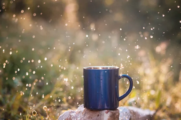 Blue mug of hot tea or coffee with milk, outdoor,