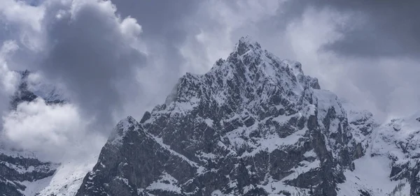 Cima di neve alpina contro un cielo cupo — Foto Stock