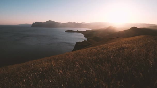 遠くの海に太陽が沈む美しい崖 ビーチでの美しい夕日 素晴らしい色 光ビームは 海の上の雲の景色を通して輝いています 海の夕日 — ストック動画