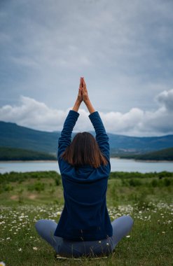 Sahada yoga yapan genç bir kadın. Doğaya karşı duyarlılık. Kendi kendine analiz ve vicdan muhasebesi. Ruhani ve duygusal bir kavram. arka plan