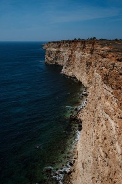 Mavi denizdeki uçurumdan güzel bir manzara. Denizde serbest kayalıkları olan inanılmaz bir sahil. Cape Fiolent, Kırım.