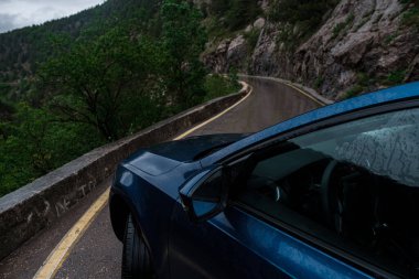 Baharda gündüz vakti yağmurlu yolda mavi araba. Ulaşım. Sisli ormanlık alanda boş bir otoyol. Trip. Tatil gezisi konsepti, uzay